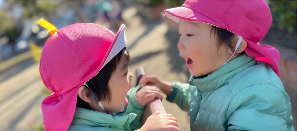 公園で2人の園児が向き合って仲良く笑っている姿