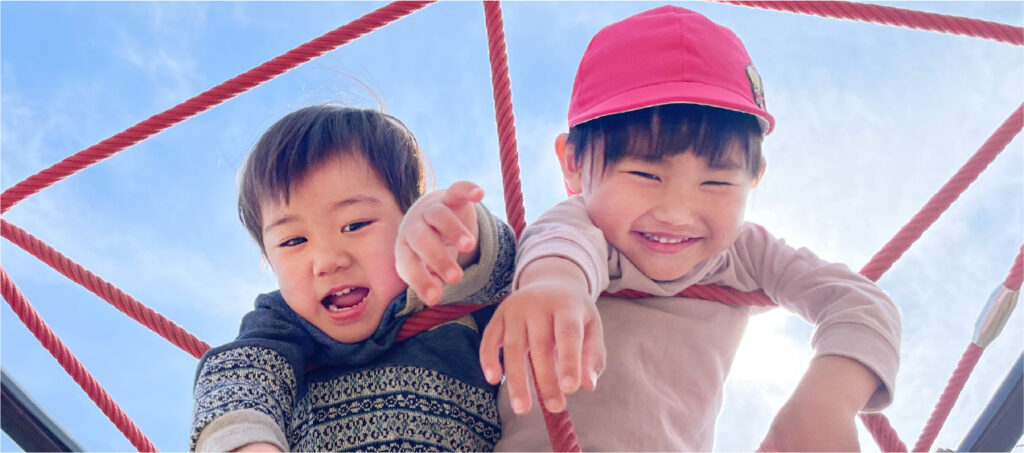 2人の園児が公園の遊具で遊んでいる姿