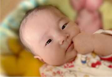乳幼児の目線写真。手が口元に添えられている。