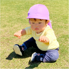 園児が公園の芝生の上でのびのび過ごしている